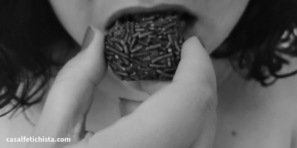Foto em preto e branco de mulher comendo brigadeiro de forma sensual