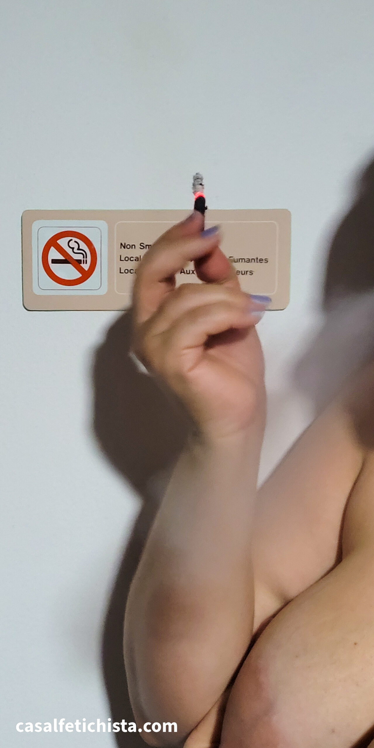 Mulher tragando cigarro Black em frente a aviso de proibição de fumo